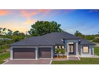 Stunning single-story home featuring a three-car garage, elegant landscaping, and modern architectural details at 10588 Kidron Ave, Englewood, FL 34224