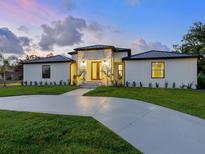 Charming single-story home with manicured lawn and a circular driveway at twilight at 180 Lookout Point Dr, Osprey, FL 34229