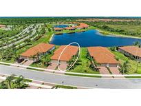 An aerial view of a townhome community with red-tiled roofs, a serene lake, and lush landscaping at 24065 Canterwood Way, Venice, FL 34293