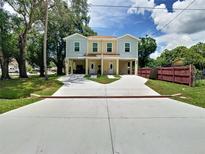 Charming two-story duplex with a large driveway, lawn, and quaint curb appeal on a sunny day at 4209 W Woodlawn Ave, Tampa, FL 33614