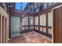 Inviting courtyard featuring brick pavers, brown siding and a stylish green front door with glass paneled entryways at 800 S Blvd Of The Presidents # 5, Sarasota, FL 34236