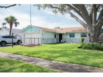 Charming home with a well-manicured lawn, mature tree, and unique stone accents at 1004 65Th W Ave, Bradenton, FL 34207