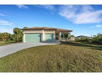 Charming single-story home featuring a manicured lawn, stone accents, and two-car garage doors at 144 Spring Dr, Rotonda West, FL 33947