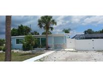 Charming single-story light blue home featuring palm trees, accent stone, and a white fence at 21403 Glendale Ave, Port Charlotte, FL 33952