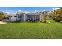 Delightful single-story home showcasing a beautifully maintained lawn, colorful landscaping, and a welcoming screened porch at 237 85Th St, Holmes Beach, FL 34217