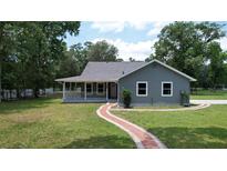 Charming home with a covered porch and a brick walkway leading to the entrance on a large lawn at 3287 Rackley Rd, Brooksville, FL 34604