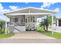 Charming home featuring a covered carport, grill, manicured lawn, and delightful landscaping with palm trees at 3333 26Th E Ave # 1104, Bradenton, FL 34208