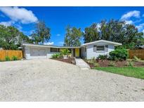 Charming single-story home featuring a yellow door, neutral paint, gravel driveway, and well-maintained landscaping at 4151 Olive Ave, Sarasota, FL 34231