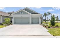 Beautiful, light-blue home showcasing a well-manicured lawn and a three-car garage at 4406 Rustling Pines Ter, Parrish, FL 34219