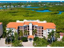Luxury condo building boasts a red tile roof and lush green surroundings with waterfront views at 5420 Eagles Point Cir # 106, Sarasota, FL 34231