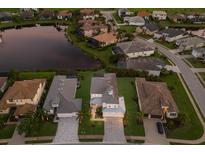 Beautiful aerial view of a quiet neighborhood with manicured lawns and a serene lake at dusk at 5718 Title Row Dr, Bradenton, FL 34210