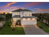 Elegant two-story home showcasing a lush, manicured lawn, paver driveway and vibrant sunset backdrop at 5718 Title Row Dr, Bradenton, FL 34210