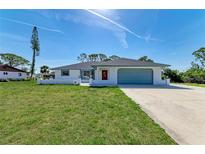 Charming one-story home with a well-maintained lawn, blue trim, red door and attached garage at 645 Liberty St, Englewood, FL 34223