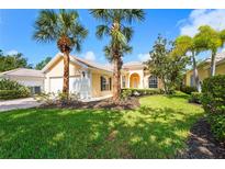 Charming single-story home featuring a tile roof, lush landscaping, and mature palm trees in a well-maintained front yard at 7716 Uliva Way, Sarasota, FL 34238