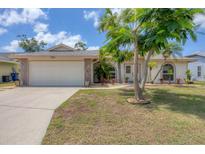 Charming single-story home featuring a two-car garage and tropical landscaping, with a well-maintained lawn at 7834 38Th E Ct, Sarasota, FL 34243