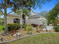 Charming home featuring a well-maintained lawn, vibrant landscaping, and decorative wagon wheel accents at 8222 Haven Harbour Way, Bradenton, FL 34212