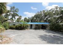 Charming single-story home with a carport and lush landscaping at 129 Pierson Ln, Sarasota, FL 34242