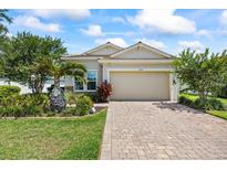 Charming single-Gathering home features a manicured lawn, brick driveway, and attached two-car garage at 13819 American Prairie Pl, Bradenton, FL 34211