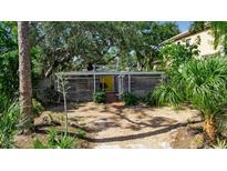 Inviting single-story home featuring a minimalist design, wooden siding, yellow front door, and xeriscaped front yard at 1677 Hyde Park St, Sarasota, FL 34239