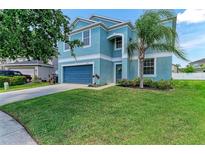 Charming two-story home with a blue exterior, well-manicured lawn, and mature palm tree at 1721 Palm Warbler Ln, Ruskin, FL 33570