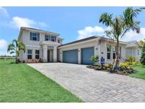Elegant home with a paver driveway, lush landscaping, and a spacious three-car garage at 17911 Palmiste Dr, Bradenton, FL 34202