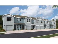 Row of modern townhomes featuring a light blue exterior, garages, and well-maintained landscaping at 2710 Pearly Banks Dr, Bradenton, FL 34208
