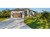 Charming single-story home featuring a manicured lawn, two-car garage, and a welcoming front entrance with modern accents at 5365 Craig Ter, Port Charlotte, FL 33981