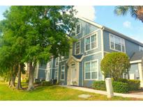 Two-story townhome with charming blue siding and well-manicured lawn and green trees at 5681 Bidwell Pkwy # 104, Sarasota, FL 34233