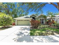 Charming one-story home with lush landscaping, green exterior, and a two-car garage at 135 Tall Trees Ct, Sarasota, FL 34232