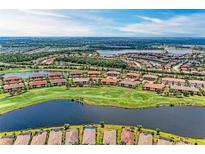 Stunning aerial view of a community with lake, golf course, and beautiful homes with red tile roofs at 13710 Messina Loop # 201, Bradenton, FL 34211