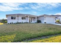 Inviting one-story home showcasing a manicured lawn, fresh landscaping, and a two-car garage at 14065 Paris Ln, Port Charlotte, FL 33981