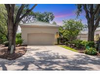 Charming home featuring a tile roof, neutral exterior paint, mature landscaping, and a spacious driveway at 2816 Breton Woods, Sarasota, FL 34235
