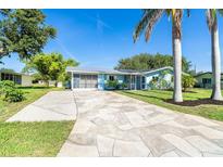 Charming one-story home with a light blue exterior, a patterned driveway and tropical landscaping at 3585 Brooklyn Ave, Port Charlotte, FL 33952