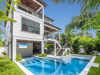 Backyard with a pool, outdoor seating, a cabana, and lush tropical foliage at 421 Alamanda Rd, Anna Maria, FL 34216