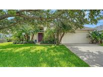 Charming home featuring a lush green lawn, mature trees, and a neatly landscaped front yard at 5044 Creekside Trl, Sarasota, FL 34243