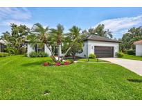 Charming single-story home featuring lush landscaping, vibrant flower beds, and a well-manicured lawn at 5285 Far Oak Cir, Sarasota, FL 34238