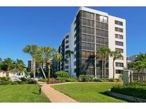 Beautiful high-rise beachfront condo building with lush tropical landscaping and a walkway to the pool at 5880 Midnight Pass Rd # 207, Sarasota, FL 34242