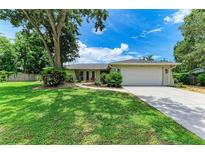 Charming single-story home with a lush green lawn, mature trees, and a paved driveway leading to a two-car garage at 7023 Woodside Oaks Cir # 1, Sarasota, FL 34231