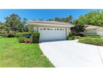 Home exterior featuring a white garage door, tiled roof, and well-maintained landscaping on a sunny day at 7023 Woodside Oaks Cir # 1, Sarasota, FL 34231