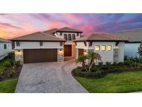Elegant home featuring a well-manicured lawn, paver driveway, and a three-car garage at 8962 Baroque Ter, Sarasota, FL 34240