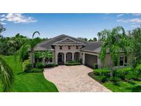 Beautiful single-Gathering home with a brick driveway, lush landscaping, and well-manicured lawn at 932 Mangrove Edge Ct, Bradenton, FL 34208