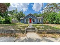 Charming blue home featuring a bright red door, well-maintained lawn, and classic architectural details at 2509 8Th W Ave, Bradenton, FL 34205