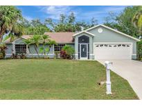Charming single-story home with lush landscaping, beautiful green lawn, and a two-car garage at 4322 Concert St, Port Charlotte, FL 33948
