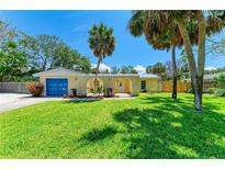 Charming yellow single-story home featuring a blue garage door and well-manicured lawn and arched entry at 5223 Shadow Lawn Dr, Sarasota, FL 34242