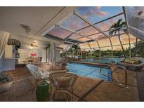 Relaxing screened pool with dining area and waterfront views at dusk at 572 Commonwealth Ln, Sarasota, FL 34242