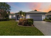 Charming one-story home featuring a well-manicured lawn, beautiful landscaping, and an attached two-car garage at 664 Planters Manor Way, Bradenton, FL 34212