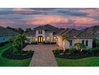 Elegant home with a brick paved driveway, manicured lawn, a two-car garage and lush landscaping at sunset at 7838 Bowspirit Way, Lakewood Ranch, FL 34202