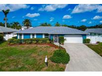 Charming blue single-story home with a grey metal roof, manicured lawn, and two-car garage at 1312 73Rd Nw St, Bradenton, FL 34209