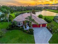 Beautiful waterfront home featuring a tile roof, lush landscaping, and a three-car garage at sunset at 312 148Th Ne Ct, Bradenton, FL 34212