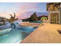 Custom infinity pool with a fire pit and lounge seating overlooking the waterway at dusk at 3799 Flamingo Ave, Sarasota, FL 34242